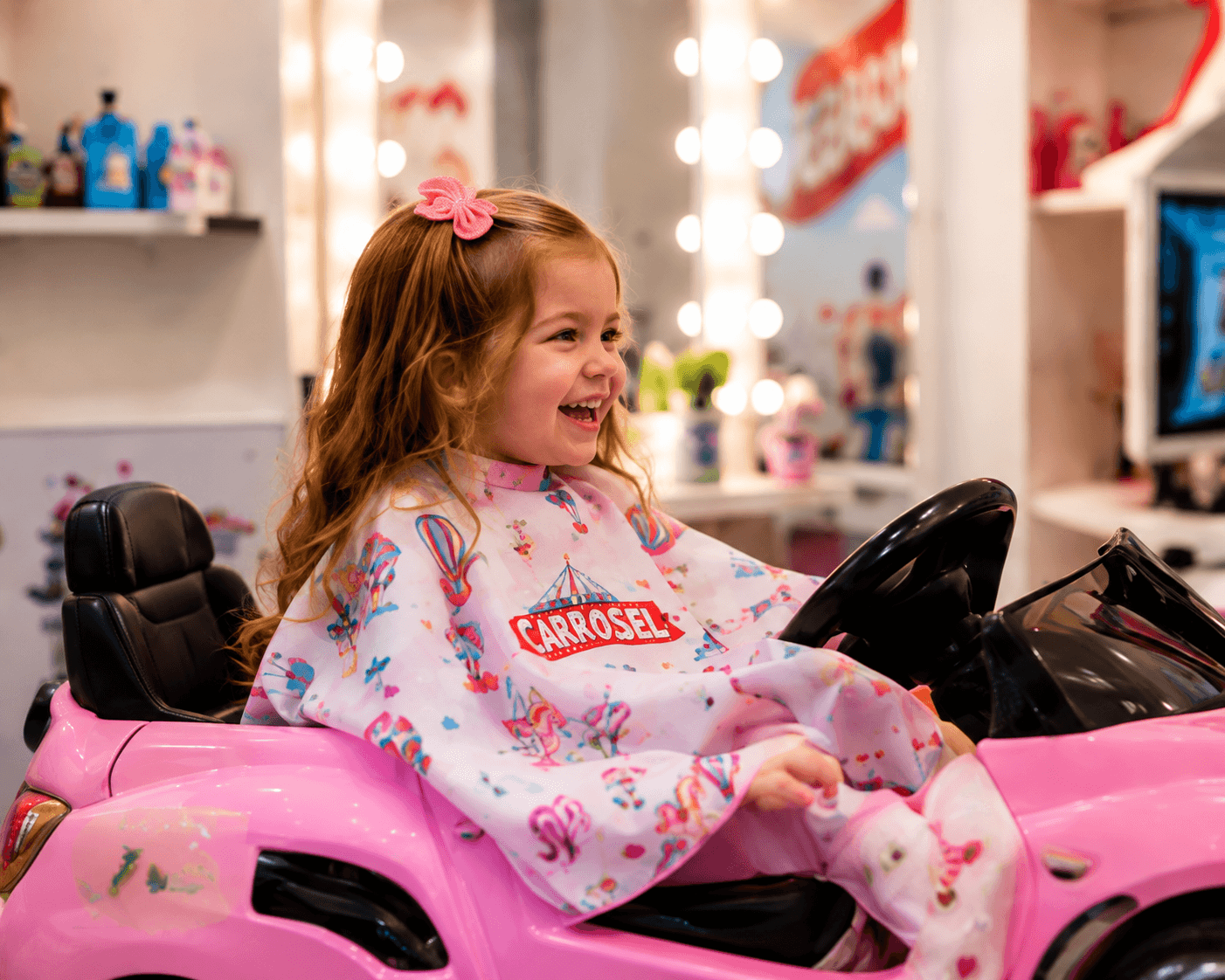 Menina a rir sentada no carro cor-de-rosa do salão