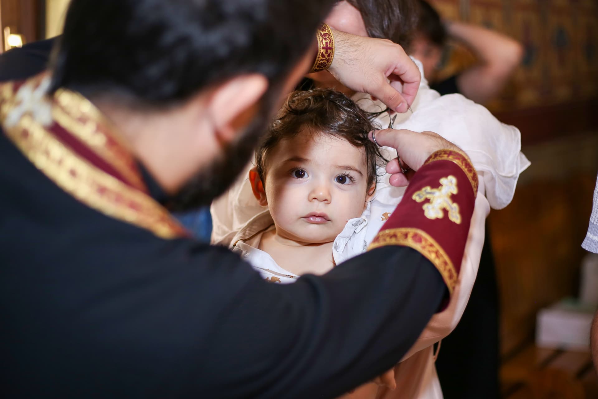 Bebé ao colo, tranquilo, enquanto lhe cortam uma madeixa de cabelo