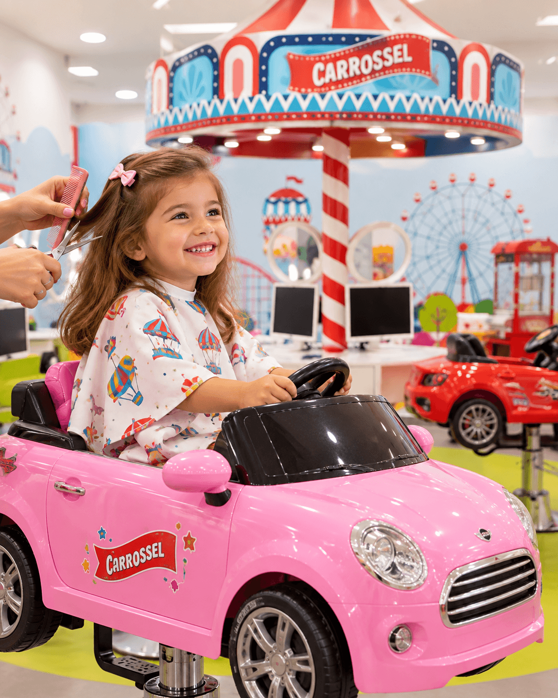 Menina de cabelo comprido a ser penteada no carro cor-de-rosa do Carrossel